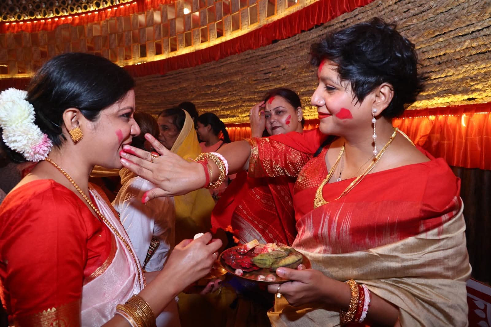 Women celebrating Sindoor Khela during Durga Puja with vermillion and festive attire