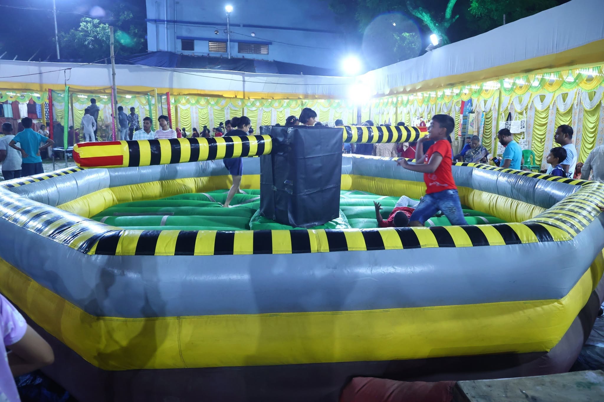 Children playing on an inflatable meltdown ride at the night festival fair