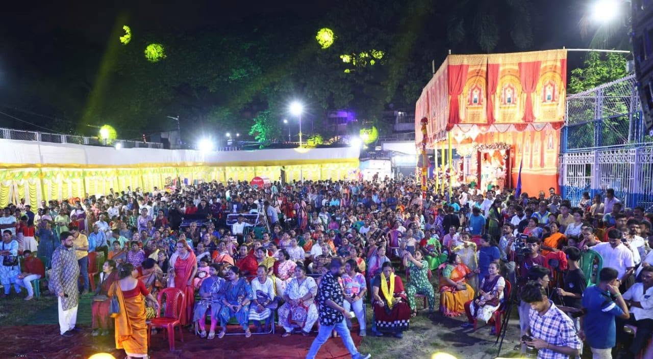 Large crowd gathered at night beside the decorated Durga Puja pandal