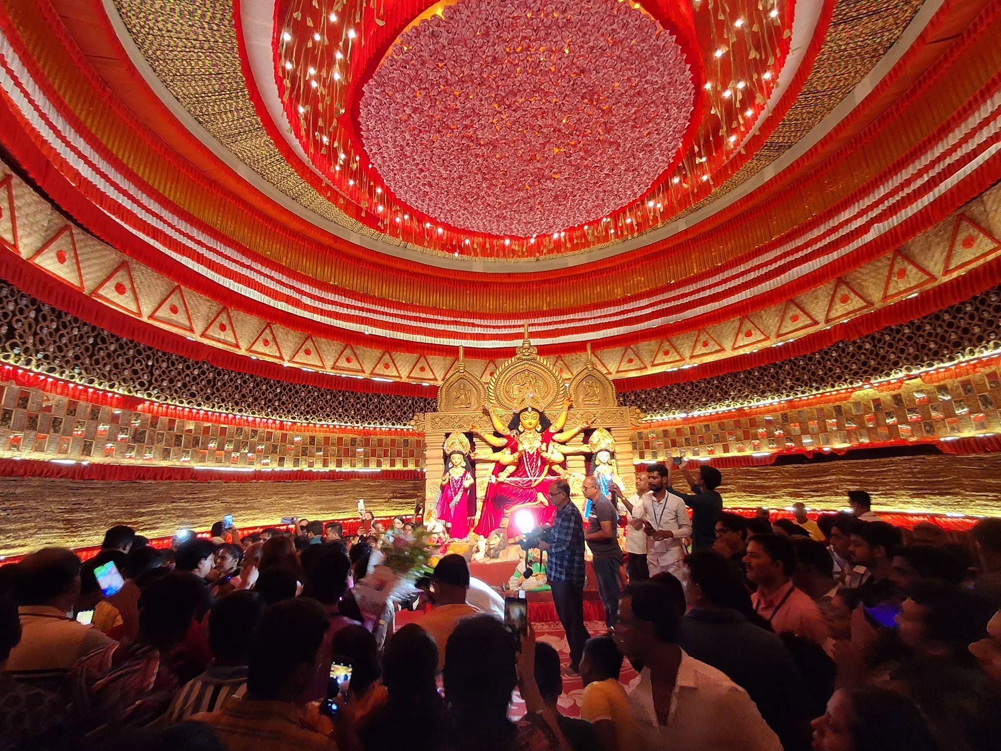 Crowd of devotees inside the ornate pandal viewing Maa Durga