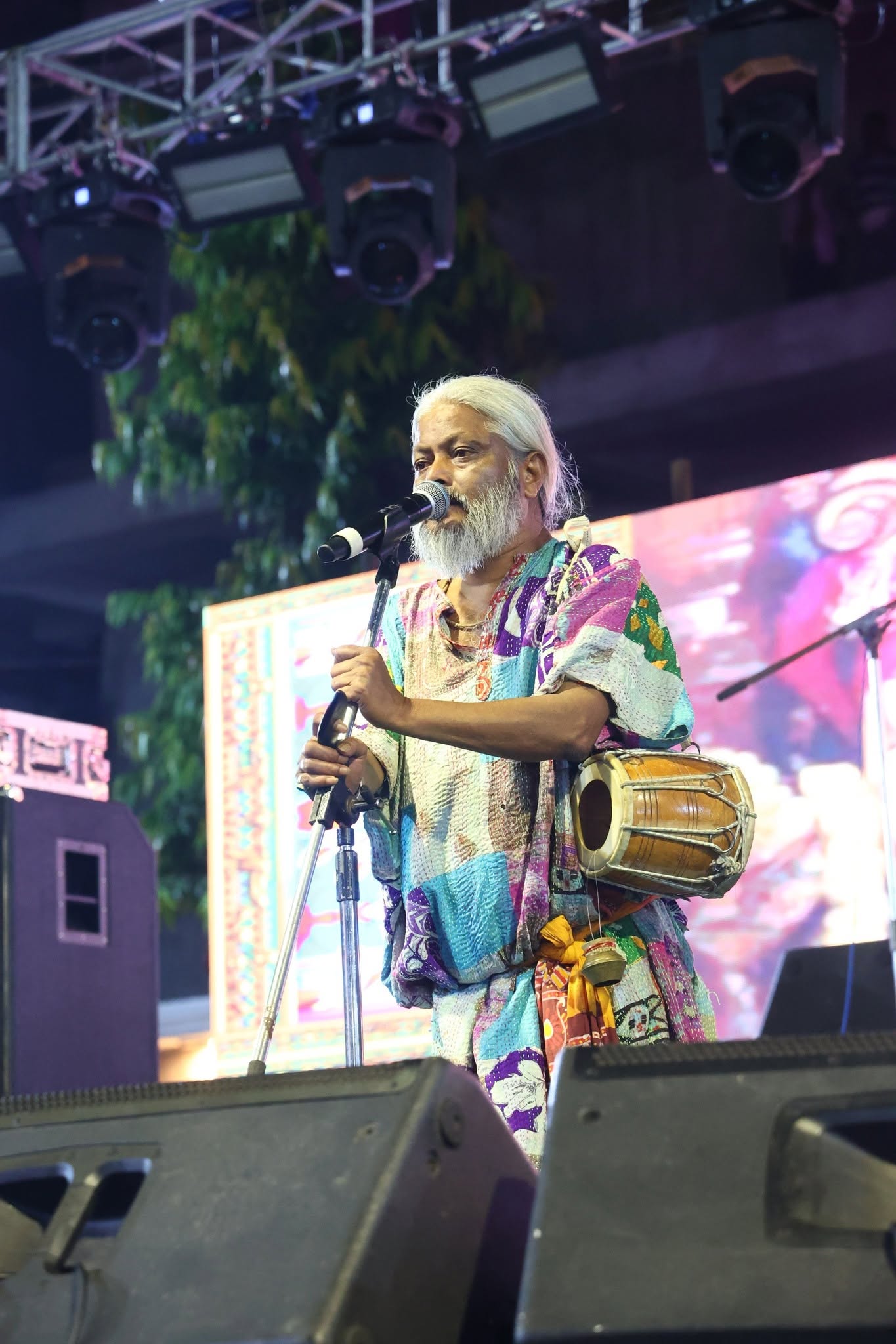 Baul folk singer with khol performing on the outdoor festival stage at night